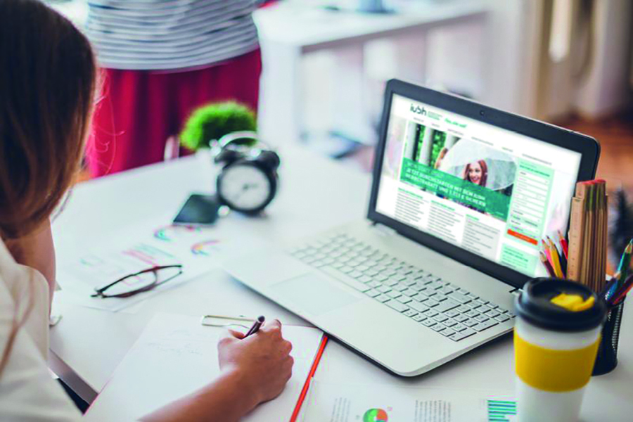 Woman taking notes while looking at website on computer