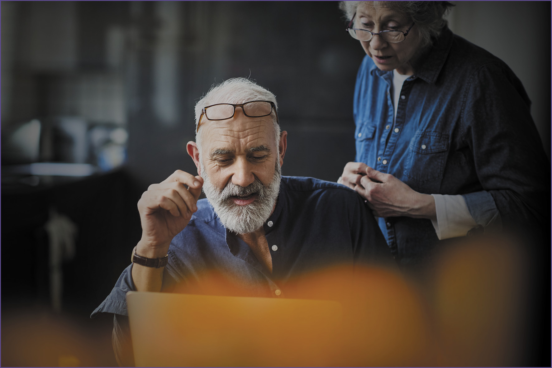Elderly man and woman talking while looking at computer screen