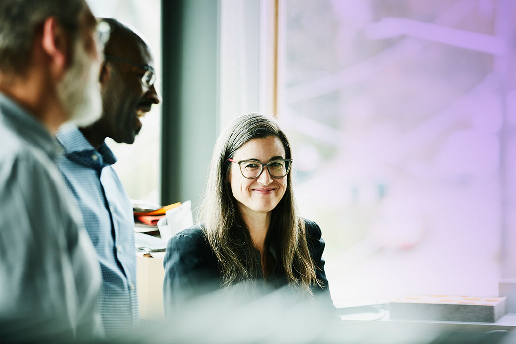 Portrait of smiling businesswoman in discussion with coworkers in office